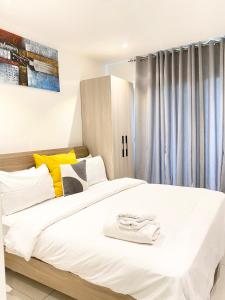 ein Schlafzimmer mit einem großen weißen Bett mit gelben Akzenten in der Unterkunft Serene Space at the Lennox in Accra