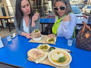 two women sitting at a table with plates of food at City Center Apartments in Haifa