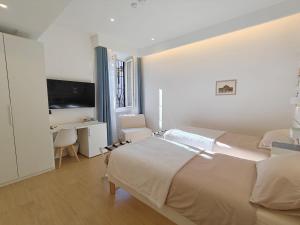 a white bedroom with two beds and a desk at La Casa di MiDa in Rome
