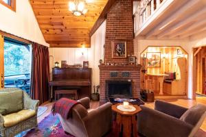 a living room with a fireplace and a piano at Contemporary Classic on a Private Mountain Lake in Lake Arrowhead