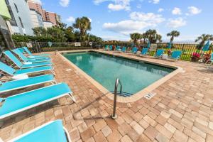 ein Swimmingpool mit blauen Liegestühlen in einem Resort in der Unterkunft Beachfront Fireplace Downtown Hot Tub King Bed in Myrtle Beach