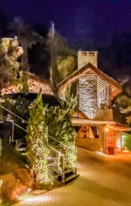 ein Haus mit Weihnachtsbäumen davor in der Unterkunft Casa Luxo p 12 pessoas ou Suite Premium 4 pessoas com jacuzzi in Campos do Jordão