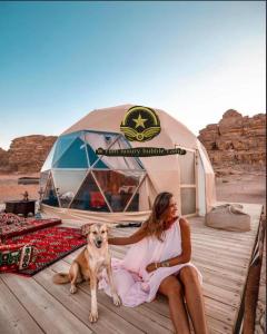 a woman and a dog sitting on a dock next to a tent at RUM W BUBBLE lUXURY CAMP in Wadi Rum