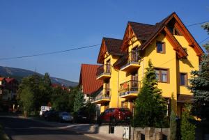 a yellow house with a brown roof at DARIA pokoje gościnne in Karpacz
