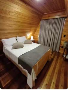 a bedroom with a large bed in a wooden room at Chalé Pôr do Sol 1 in Nova Veneza