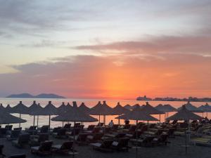 a group of chairs and umbrellas on the beach at sunset at SEA SIDE FAMILY APARTMENTs in Vlorë