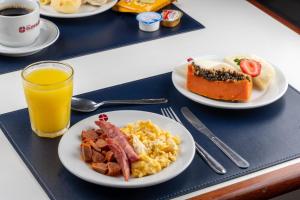 a tray with plates of breakfast food and a glass of orange juice at Hotel Euro Suite Campinas by Nacional Inn - Próximo ao Cambuí in Campinas