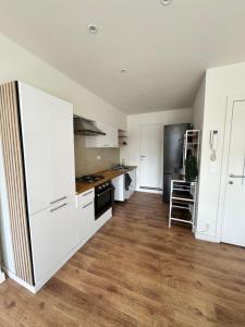 een keuken met witte kasten en een houten vloer bij Grand Duplex avec 2 chambres in Charleroi +9 foto's