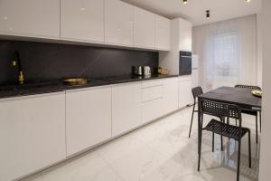 a kitchen with white cabinets and a table and chairs at Apartament Golden Prestige in Głogów