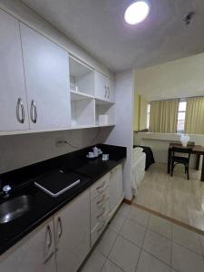 une cuisine avec des armoires blanches et un évier et une chambre dans l'établissement Bahia Iguatemi Business Flats, à Salvador