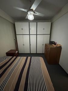 Schlafzimmer mit einem Bett, weißen Schränken und einem Deckenventilator in der Unterkunft Departamento 1 dormitorio in Santa Fe