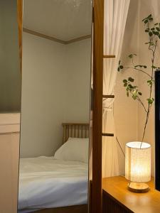 ein Schlafzimmer mit einem Bett und einem Spiegel mit einer Lampe in der Unterkunft Hommie Ground Seonyudo in Seoul