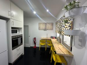 a kitchen with a wooden table and yellow chairs at Casa Physalis in Ponta Delgada