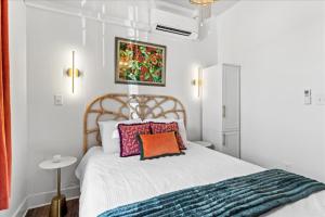 a bedroom with a white bed with an orange pillow at Old Spanish House Suite A Downtown Retreat in Biloxi