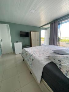 a bedroom with a bed and a large window at Pousada Pôr do Sol in Lapa
