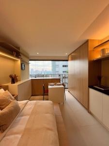 a bedroom with a large bed and a kitchen at AP aconchegante na Vila Madalena in Sao Paulo