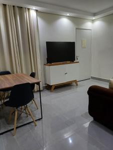 a living room with a television and a table and chairs at Apartamento 2 quartos Ótima Localização in Uberlândia +14 photos