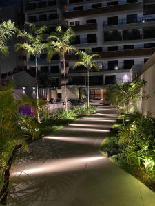 a walkway with palm trees in front of a building at Vert House in João Pessoa