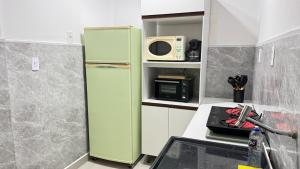 a green refrigerator in a kitchen with a microwave at Apartamento Pé na Praça Centro Serra Neg in Serra Negra
