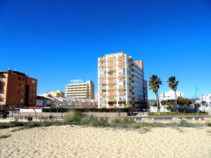 ein hohes Gebäude neben einem Strand mit Palmen in der Unterkunft Europeñiscola playavacaciones in Benicarló