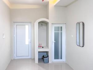 a white room with a door and a mirror at RedDoorz Syariah near Alun-Alun Tanjunganom Nganjuk in Warujayeng