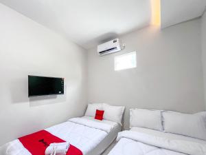 a small room with two beds and a flat screen tv at RedDoorz Syariah near Alun-Alun Tanjunganom Nganjuk in Warujayeng