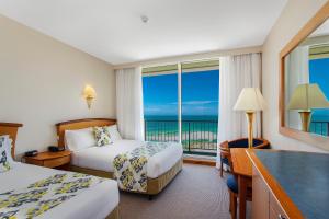 a hotel room with two beds and a view of the ocean at Noah's On the Beach in Newcastle