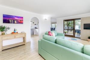 un salon avec un canapé et une télévision dans l'établissement Songbirds on Bribie, à Bongaree