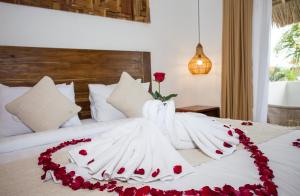 a bed with white sheets and a rose on it at Baliterraneo Boutique Resort in Seminyak