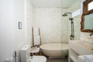 a bathroom with a tub and a toilet and a sink at Baliterraneo Boutique Resort in Seminyak