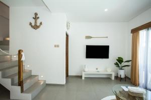 a white living room with stairs and a tv at Baliterraneo Boutique Resort in Seminyak