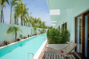a swimming pool with a bench and palm trees at Baliterraneo Boutique Resort in Seminyak