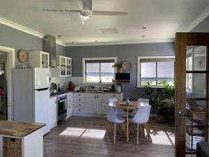 eine Küche mit weißen Geräten sowie einem Tisch und Stühlen in der Unterkunft Blue Gate Cottage in Indigo Upper