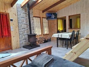 a living room with a fireplace and a table and a stove at alojamientos CM in Tolhuin