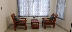 three chairs and a table in front of a window at Iniyan Nestle in Yercaud
