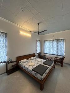 1 dormitorio con 1 cama, 2 sillas y ventanas en Iniyan Nestle, en Yercaud