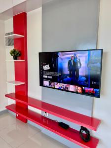 un téléviseur à écran plat sur un centre de divertissement rouge dans l'établissement Cozy 1BR Condo in Manila Near US Embassy and Robinsons Place Manila, à Manille