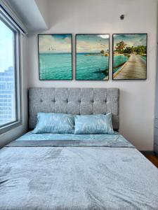 - une chambre avec quatre photos suspendues au-dessus d'un lit dans l'établissement Cozy 1BR Condo in Manila Near US Embassy and Robinsons Place Manila, à Manille