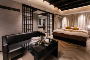 a bedroom with a bed and a couch and a table at ホテルジップスタイル in Sendohira