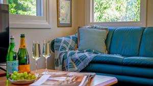 a living room with a blue couch and a table with wine glasses at Centennial Views Apartment in Bowral