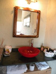 baño con lavabo de cuenco rojo y espejo en Brisas del Champaquí en La Cumbrecita