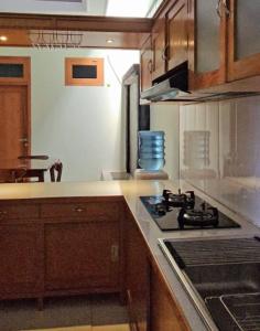 a kitchen with a stove and a counter top at Inti Homestay 3 Kamar Fasilitas Lengkap in Gondowulung