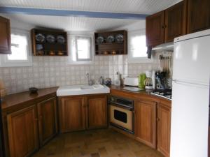 una cucina con armadi in legno, lavandino e frigorifero di Maison à Barbâtre proche plage pour 6 pers., animaux admis - FR-1-823-17 a Barbâtre Altre 8 foto