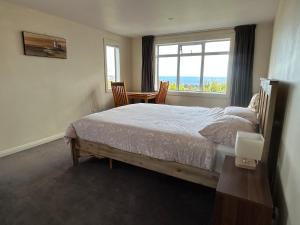 una camera da letto con un letto, un tavolo e una finestra di Sea Views Studio a Dunedin