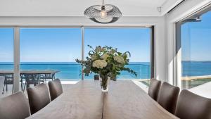 a dining room with a table with a vase of flowers at 'Sea Mist' by HolidayCo in Hardys Bay