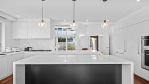 a white kitchen with a large white counter top at 'Sea Mist' by HolidayCo in Hardys Bay