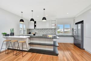 a kitchen with white walls and wood floors at Bombora Beach House at Caves Beach Villas in Caves Beach