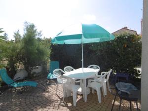 a table and chairs with an umbrella on a patio at Charmante maisonnette proche plage - Animaux admis - FR-1-823-117 in Barbâtre +3 photos