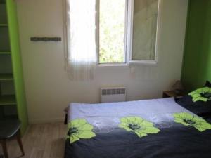 a bedroom with a bed with a blue blanket with flowers on it at Maisonnette à Barbâtre, proche plage, animaux admis, 2-4 pers. - FR-1-823-118 in Barbâtre