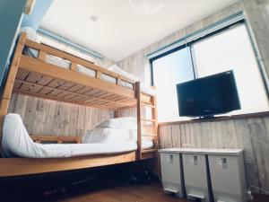 a bedroom with two bunk beds and a flat screen tv at イーストコート長崎 in Tokyo